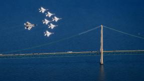 Military aircraft fly over Michigan's Mackinac Bridge, highlighting the state's aerospace and defense industry leadership.