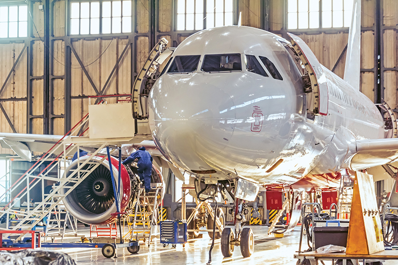 An airplane technician works on an airplane engine in a hangar.